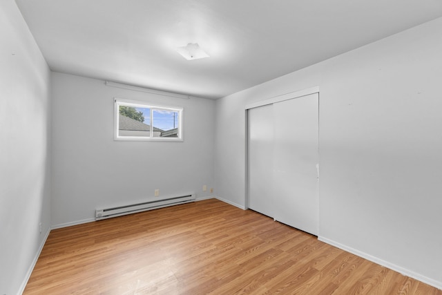 5218 E Commerce Ave, Spokane, WA 99212 - unfurnished bedroom featuring a baseboard radiator, light wood-style flooring, and a closet