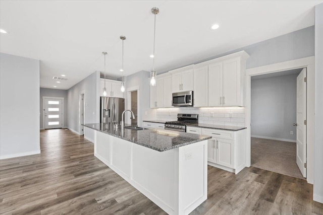 4919 E Grace Ave, Spokane, WA 99217 - kitchen featuring appliances with stainless steel finishes, an island with sink, decorative backsplash, white cabinetry, and recessed lighting