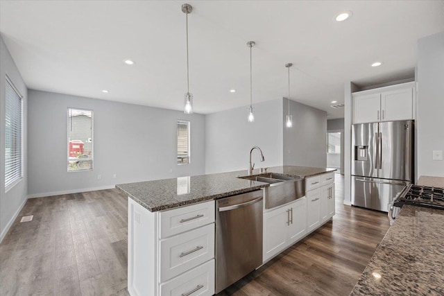 4919 E Grace Ave, Spokane, WA 99217 - kitchen featuring stainless steel appliances, dark wood-type flooring, dark stone countertops, pendant lighting, and an island with sink