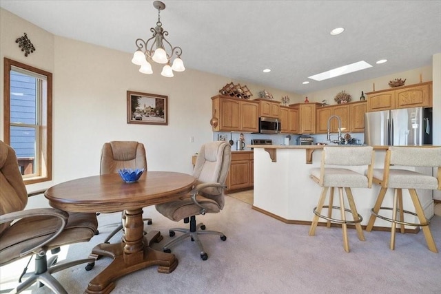 8710 E Sugar Pine Ln, Spokane, WA 99217 - kitchen with stainless steel appliances, a kitchen breakfast bar, a skylight, light countertops, and light colored carpet