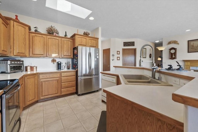 8710 E Sugar Pine Ln, Spokane, WA 99217 - kitchen featuring stainless steel appliances, a skylight, light countertops, light tile patterned floors, and recessed lighting