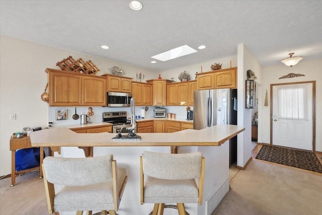 8710 E Sugar Pine Ln, Spokane, WA 99217 - kitchen featuring appliances with stainless steel finishes, a skylight, light carpet, a kitchen bar, and recessed lighting