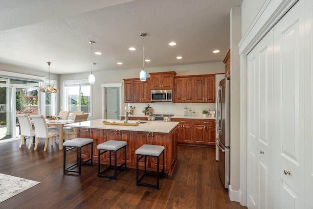 705 W Basalt Ridge Dr, Spokane, WA 99224 - kitchen with stainless steel appliances, recessed lighting, brown cabinets, light countertops, and a kitchen breakfast bar
