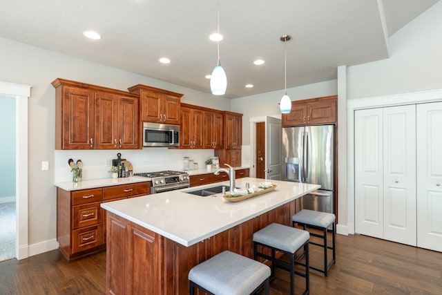 705 W Basalt Ridge Dr, Spokane, WA 99224 - kitchen featuring appliances with stainless steel finishes, brown cabinetry, a breakfast bar, dark wood finished floors, and recessed lighting