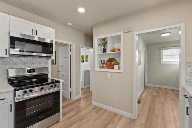 1115 E Everett Ave, Spokane, WA 99207 - kitchen with appliances with stainless steel finishes, white cabinets, light wood-style flooring, backsplash, and light countertops