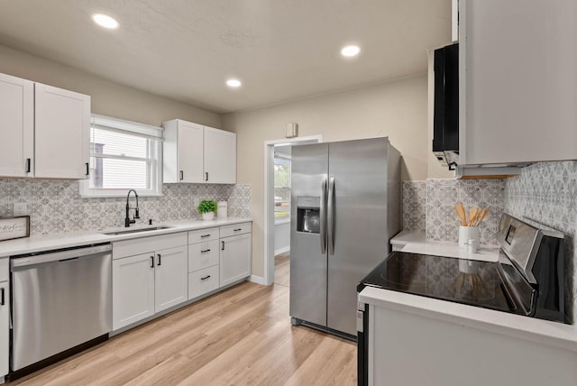 1115 E Everett Ave, Spokane, WA 99207 - kitchen with stainless steel appliances, light countertops, white cabinetry, light wood-style floors, and backsplash