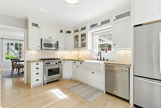 914 E 17th Ave, Spokane, WA 99203 - kitchen featuring appliances with stainless steel finishes, light wood-style floors, decorative backsplash, and light stone countertops