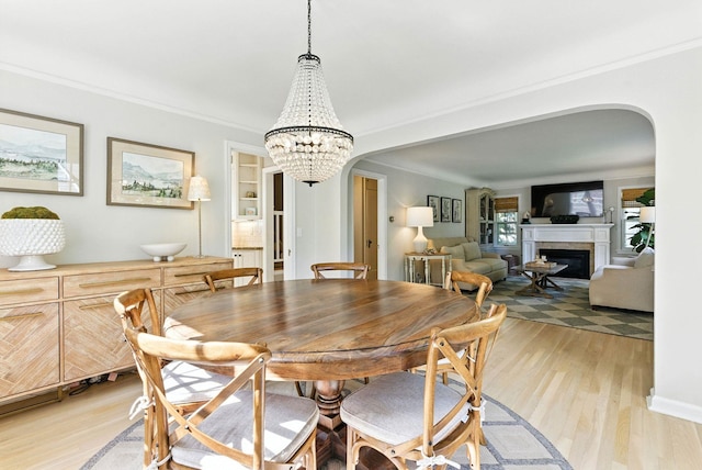 914 E 17th Ave, Spokane, WA 99203 - dining area with arched walkways, light wood finished floors, ornamental molding, a chandelier, and a glass covered fireplace