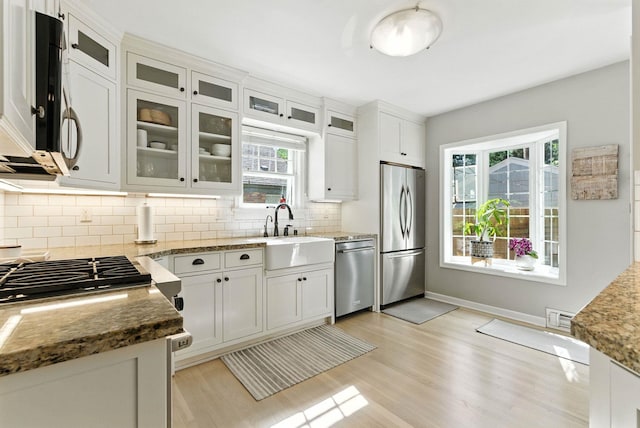 914 E 17th Ave, Spokane, WA 99203 - kitchen featuring appliances with stainless steel finishes, tasteful backsplash, light wood finished floors, light stone countertops, and healthy amount of natural light