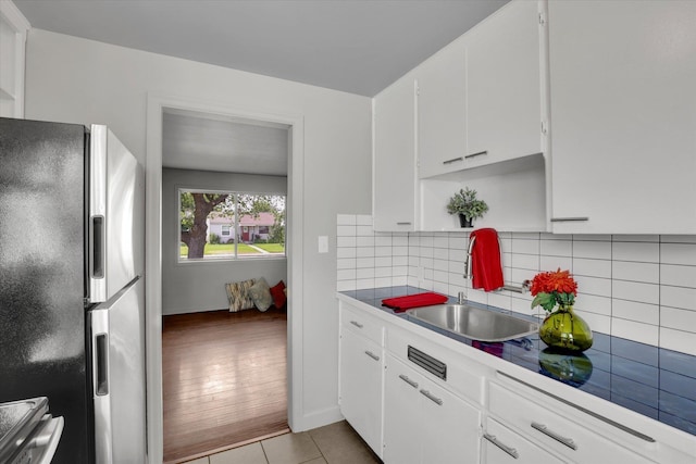 5704 N Milton St, Spokane, WA 99205 - kitchen featuring freestanding refrigerator, white cabinetry, backsplash, light tile patterned flooring, and light countertops