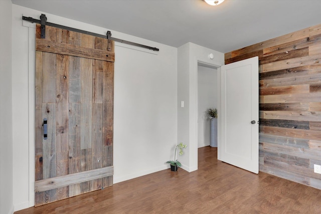 5704 N Milton St, Spokane, WA 99205 - unfurnished bedroom featuring a barn door, wood walls, and wood finished floors