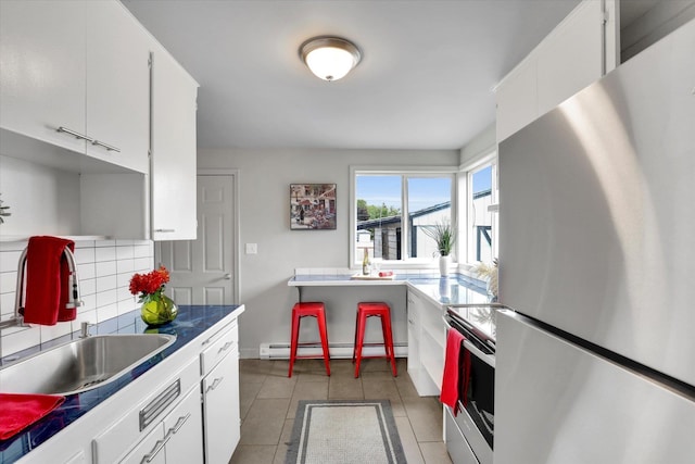 5704 N Milton St, Spokane, WA 99205 - kitchen with freestanding refrigerator, range with electric cooktop, a baseboard heating unit, decorative backsplash, and white cabinets