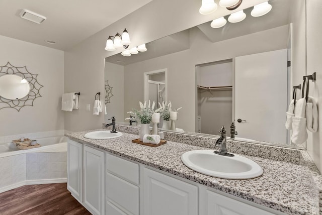 14 W Elcliff Ave, Spokane, WA 99218 - bathroom featuring double vanity, wood finished floors, a garden tub, a walk in closet, and a shower with door