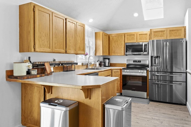 5706 W Excell Ave, Spokane, WA 99208 - kitchen featuring appliances with stainless steel finishes, a peninsula, light wood finished floors, lofted ceiling, and a breakfast bar area