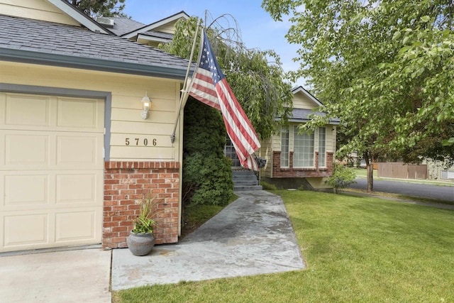 5706 W Excell Ave, Spokane, WA 99208 - doorway to property featuring a lawn, brick siding, roof with shingles, and an attached garage