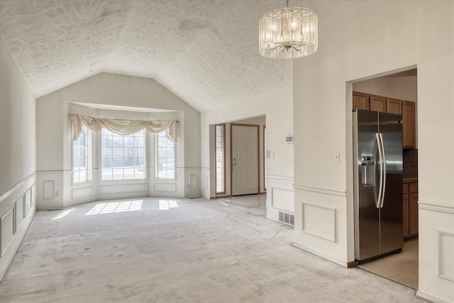 6919 N Pine Rock Pl, Spokane, WA 99208 - unfurnished dining area featuring a textured ceiling, a decorative wall, a chandelier, light colored carpet, and lofted ceiling