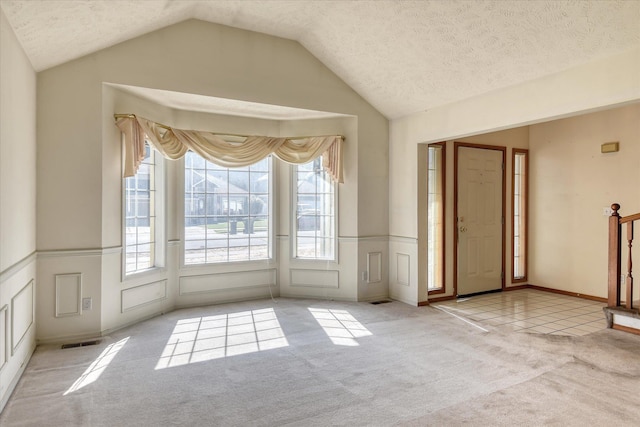 6919 N Pine Rock Pl, Spokane, WA 99208 - carpeted empty room with lofted ceiling, wainscoting, a textured ceiling, and a decorative wall