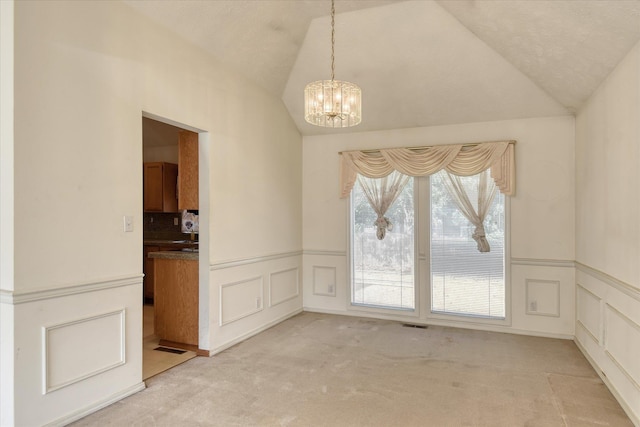 6919 N Pine Rock Pl, Spokane, WA 99208 - unfurnished dining area with light colored carpet, a chandelier, vaulted ceiling, wainscoting, and a decorative wall
