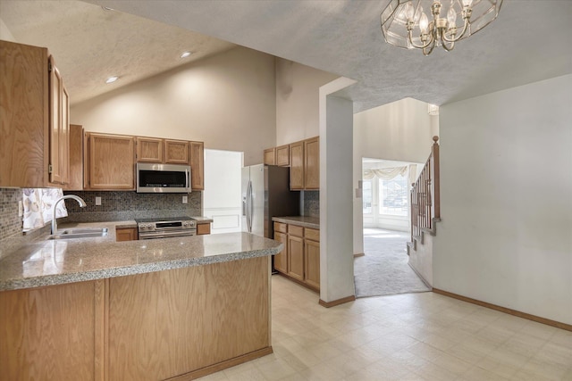 6919 N Pine Rock Pl, Spokane, WA 99208 - kitchen with stainless steel appliances, light floors, backsplash, a peninsula, and high vaulted ceiling