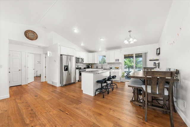17609 E 2nd Ln, Spokane Valley, WA 99016 - kitchen featuring appliances with stainless steel finishes, vaulted ceiling, a chandelier, a breakfast bar, and white cabinets