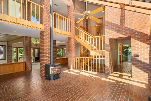 6624 S Ben Burr Rd, Spokane, WA 99223 - unfurnished living room with brick flooring, a towering ceiling, a wood stove, ceiling fan, and brick wall