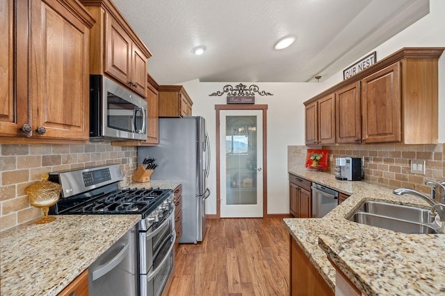 8918 E Clearview Ln, Spokane, WA 99217 - kitchen featuring stainless steel appliances, brown cabinetry, light stone countertops, decorative backsplash, and vaulted ceiling