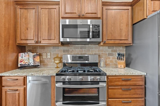 8918 E Clearview Ln, Spokane, WA 99217 - kitchen with stainless steel appliances, backsplash, and brown cabinetry