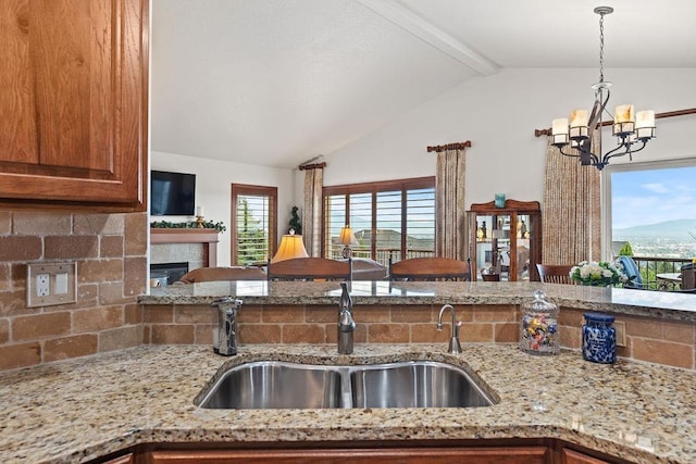 8918 E Clearview Ln, Spokane, WA 99217 - kitchen featuring a chandelier, light stone countertops, pendant lighting, a fireplace, and tasteful backsplash