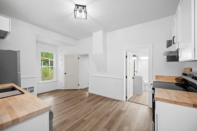2304 E 6th Ave, Spokane, WA 99202 - kitchen with range with electric cooktop, butcher block counters, freestanding refrigerator, extractor fan, and light wood finished floors