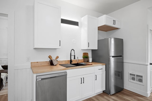2304 E 6th Ave, Spokane, WA 99202 - kitchen featuring appliances with stainless steel finishes, light wood-style flooring, a wainscoted wall, white cabinets, and heating unit