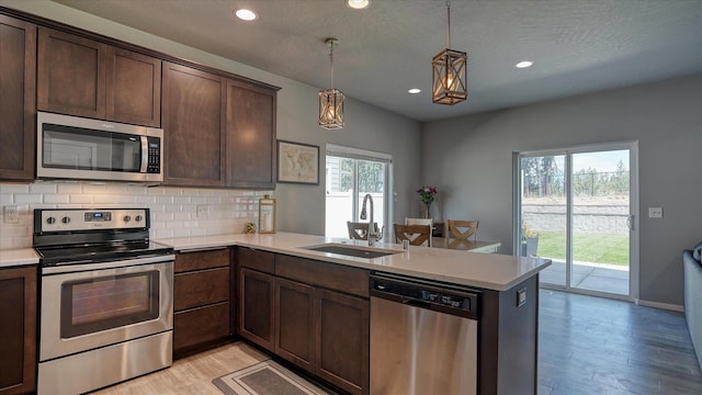 7169 S Parkridge Blvd, Spokane, WA 99224 - kitchen with stainless steel appliances, a peninsula, light wood finished floors, backsplash, and light countertops