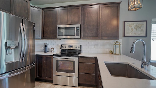 7169 S Parkridge Blvd, Spokane, WA 99224 - kitchen featuring appliances with stainless steel finishes, dark brown cabinets, tasteful backsplash, light stone countertops, and pendant lighting