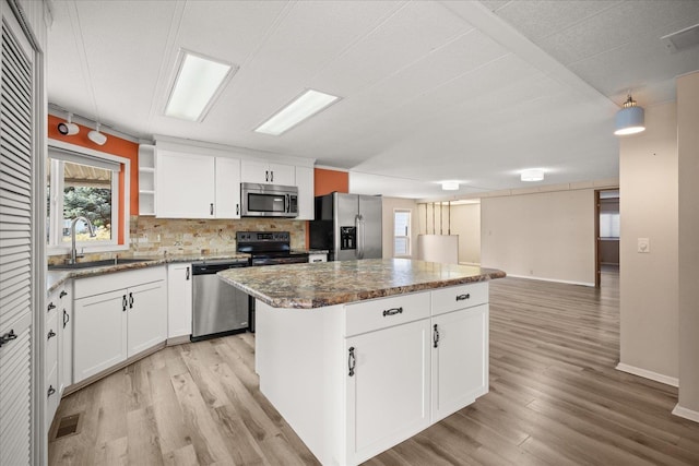 18822 E Montgomery Dr, Otis Orchards, WA 99027 - kitchen with appliances with stainless steel finishes, a kitchen island, light wood finished floors, and backsplash