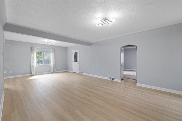 2224 N Lily Rd, Spokane, WA 99212 - unfurnished living room featuring arched walkways, a textured ceiling, and light wood-type flooring