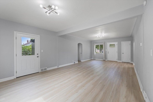2224 N Lily Rd, Spokane, WA 99212 - unfurnished living room featuring arched walkways, light wood finished floors, and a textured ceiling