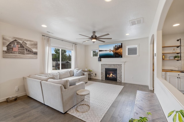 1024 W Staples Rd, Post Falls, ID 83854 - living room with arched walkways, a ceiling fan, wood finished floors, a tiled fireplace, and recessed lighting