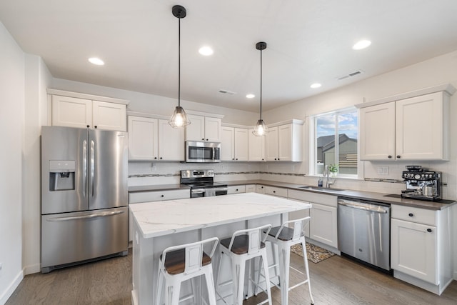 1024 W Staples Rd, Post Falls, ID 83854 - kitchen with appliances with stainless steel finishes, decorative backsplash, a kitchen island, wood finished floors, and recessed lighting