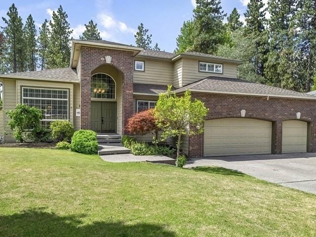 4332 S Greystone Ln, Spokane, WA 99223 - view of front of house with brick siding, a front lawn, concrete driveway, a garage, and a shingled roof