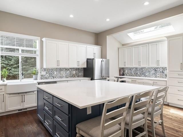 4332 S Greystone Ln, Spokane, WA 99223 - kitchen featuring freestanding refrigerator, white cabinetry, a kitchen island, a kitchen bar, and decorative backsplash