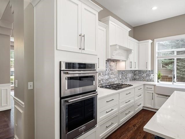 4332 S Greystone Ln, Spokane, WA 99223 - kitchen with stainless steel appliances, dark wood-style floors, white cabinetry, tasteful backsplash, and light stone counters