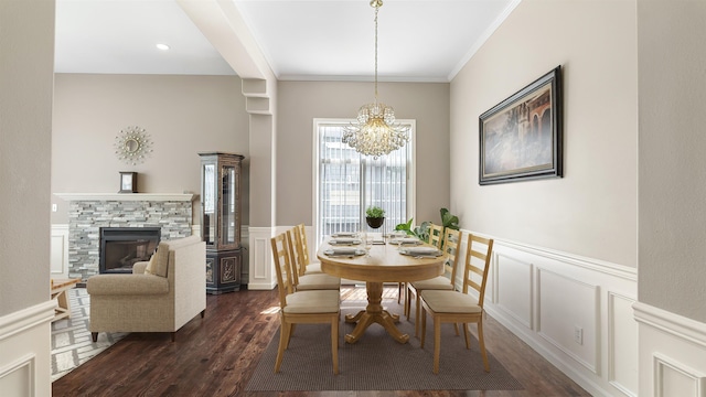 4332 S Greystone Ln, Spokane, WA 99223 - dining space with dark wood-style flooring, a chandelier, a stone fireplace, a decorative wall, and a wainscoted wall
