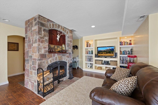 5808 N Hermosa Cir, Otis Orchards, WA 99027 - living room featuring a textured ceiling, wood finished floors, a fireplace, built in features, and arched walkways
