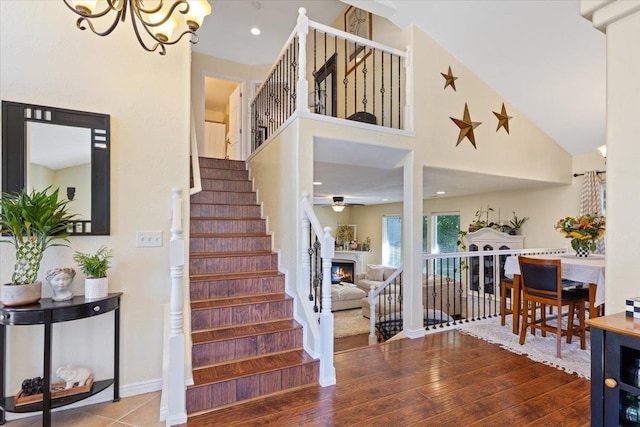 5808 N Hermosa Cir, Otis Orchards, WA 99027 - staircase featuring a chandelier, a ceiling fan, wood finished floors, a lit fireplace, and a high ceiling