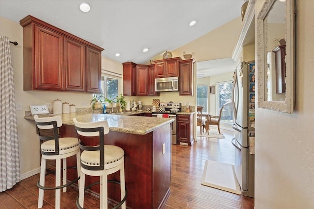 5808 N Hermosa Cir, Otis Orchards, WA 99027 - kitchen with stainless steel appliances, a peninsula, vaulted ceiling, dark wood-style floors, and a kitchen bar