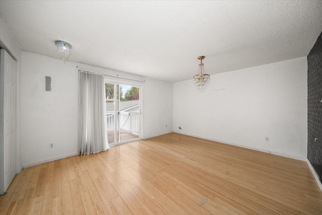 415 E Shiloh Hills Dr, Spokane, WA 99208 - unfurnished room with light wood-style flooring, a chandelier, and a textured ceiling