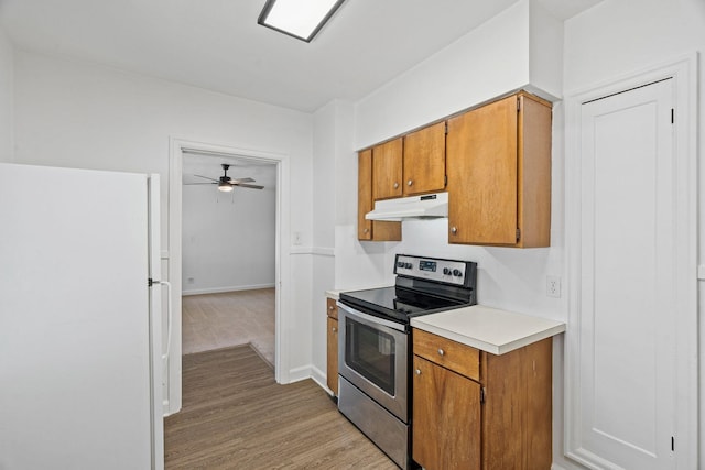 5504 N Post St, Spokane, WA 99205 - kitchen with freestanding refrigerator, stainless steel electric range, under cabinet range hood, light countertops, and brown cabinets