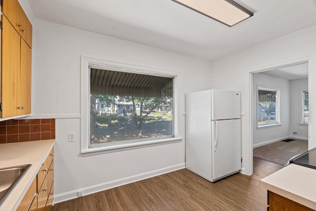 5504 N Post St, Spokane, WA 99205 - kitchen with freestanding refrigerator, dark wood-style flooring, light countertops, tasteful backsplash, and brown cabinetry