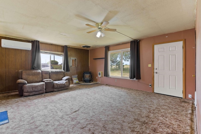 2510 N Rambo Rd, Spokane, WA 99224 - carpeted living area with a wall mounted AC, a wood stove, a ceiling fan, wooden walls, and a textured ceiling