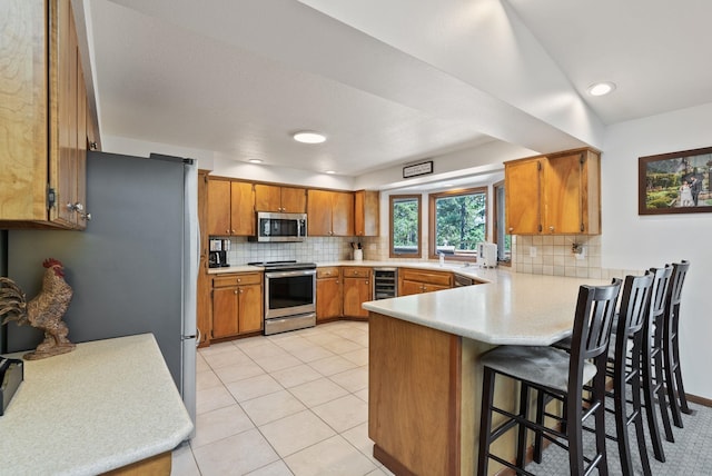 5321 Pinebrook Ct, Spokane, WA 99206 - kitchen with appliances with stainless steel finishes, wine cooler, a peninsula, brown cabinetry, and tasteful backsplash
