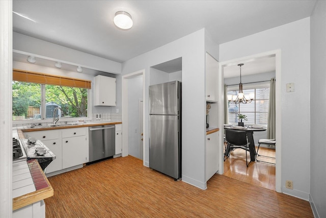 1501 S Maple St, Spokane, WA 99203 - kitchen featuring stainless steel appliances, white cabinets, a chandelier, and light wood-style floors